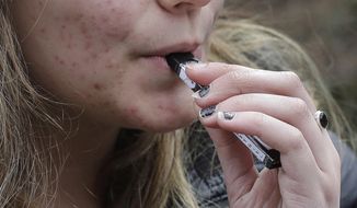  In this April 11, 2018, file photo, a high school student uses a vaping device near a school campus in Cambridge, Mass. California Gov. Gavin Newsom will announce an executive action Monday, Sept. 16, 2019, to confront youth heath concerns related to vaping.  (AP Photo/Steven Senne, File) **FILE**
