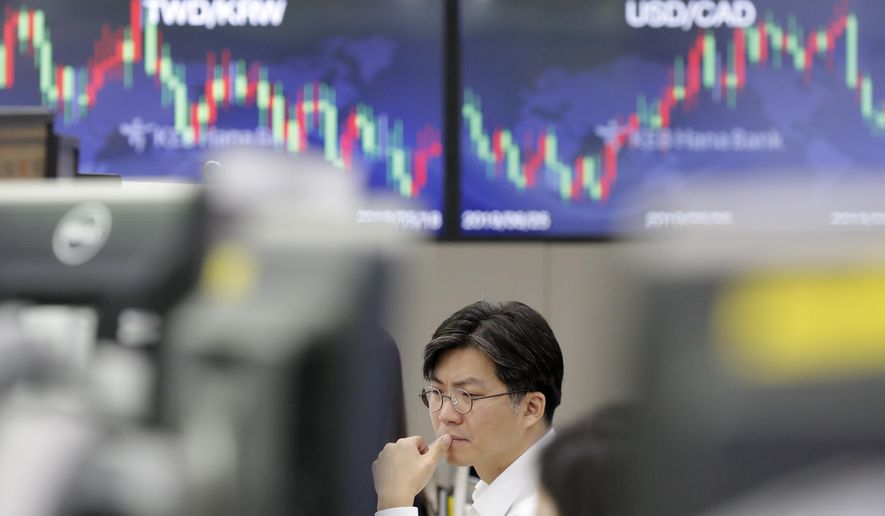 A currency trader watches the computer monitors near the screens showing the foreign exchange rates at the foreign exchange dealing room in Seoul, South Korea, Monday, Sept. 16, 2019. An attack on a critical Saudi Arabia oil plant has pushed crude prices sharply higher, though they moderated on expectations that reserves will help bridge any shortfalls in output.(AP Photo/Lee Jin-man)
