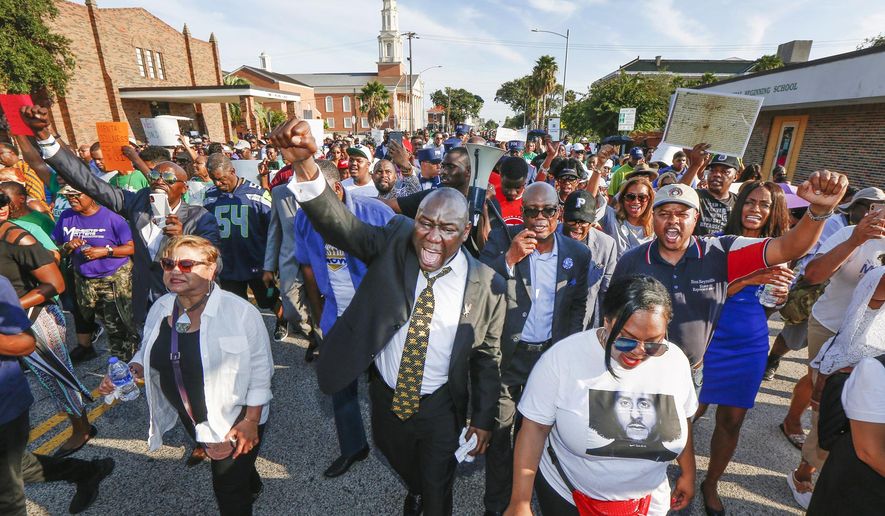 Attorney Benjamin Crump, center, and the Bishop James Dixon, behind, lead supporters of Donald Neely, the disabled man arrested and led by a rope by two mounted Galveston police officers on Aug. 3, on a march down 23rd Street, Sunday, Sept. 15, 2019, in Galveston, Texas. Marissa Barnett, City of Galveston, estimated about 250 gathered for the protest. (Steve Gonzales/Houston Chronicle via AP)