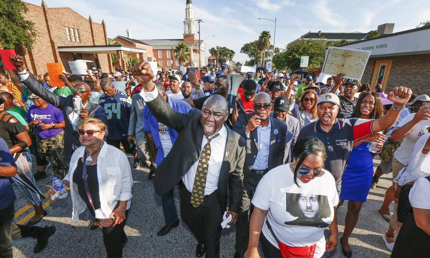 Attorney Benjamin Crump, center, and the Bishop James Dixon, behind, lead supporters of Donald Neely, the disabled man arrested and led by a rope by two mounted Galveston police officers on Aug. 3, on a march down 23rd Street, Sunday, Sept. 15, 2019, in Galveston, Texas. Marissa Barnett, City of Galveston, estimated about 250 gathered for the protest. (Steve Gonzales/Houston Chronicle via AP)