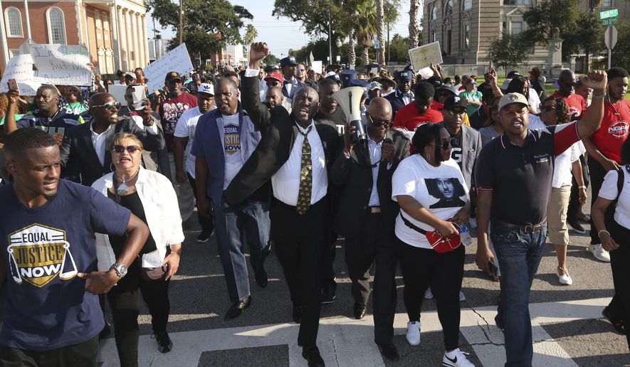 Attorney Benjamin Crump, center, chants "Justice for Donald Neely," as he and Bishop James Dixon, pastor of The Community Of Faith Church in Houston, lead a march down 23rd Street in Galveston, Texas, Sunday, Sept. 15, 2019. About 250 demonstrators joined Crump and Dixon to demand the release of police body camera videos related to the Aug. 3 arrest of Neely, who was handcuffed, attached to a lead, and then walked to a staging area between the officers' two horses. (Jennifer Reynolds/The Galveston County Daily News via AP)
