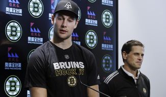 Boston Bruins defenseman Brandon Carlo speaks, as General Manager Don Sweeney listens during a news conference at the hockey team&#x27;s practice facility, Tuesday, Sept. 17, 2019, in Boston. The Bruins have signed Carlo to a two-year contract with an annual NHL cap hit of $2.85 million. Carlo, 22, skated in 72 games with the Bruins in 2018-19. (AP Photo/Elise Amendola)