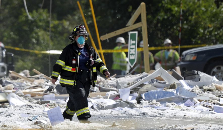 A firefighter walks through the scene of an explosion Monday, Sept. 16, 209, in Farmington, Maine. Officials say a town's fire chief is among the injured in a propane explosion that killed a firefighter. State public safety spokesman Steve McCausland said after Monday morning's explosion at a nonprofit center in Farmington that multiple people remain hospitalized. (AP Photo/Robert F. Bukaty)