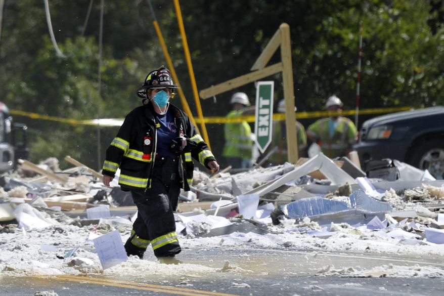A firefighter walks through the scene of an explosion Monday, Sept. 16, 209, in Farmington, Maine. Officials say a town's fire chief is among the injured in a propane explosion that killed a firefighter. State public safety spokesman Steve McCausland said after Monday morning's explosion at a nonprofit center in Farmington that multiple people remain hospitalized. (AP Photo/Robert F. Bukaty)