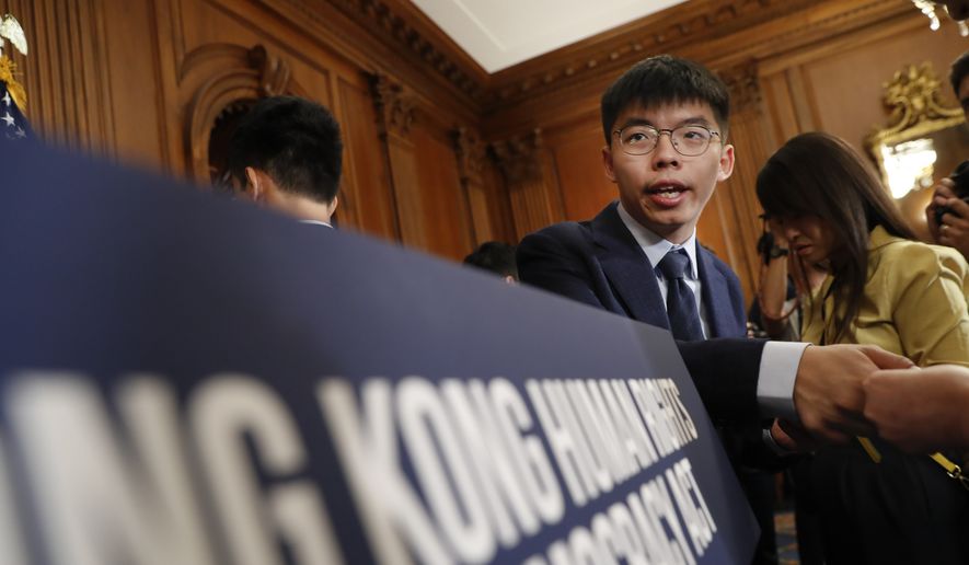 Hong Kong activist Joshua Wong, hands out his business card following a news conference on human rights in Hong Kong on Capitol Hill in Washington, Wednesday, Sept. 18, 2019. (AP Photo/Pablo Martinez Monsivais)