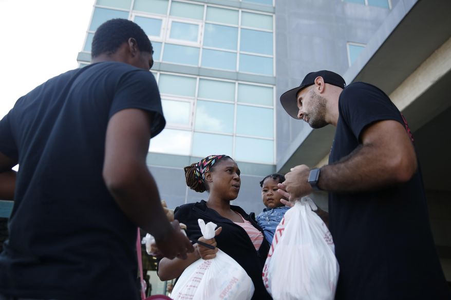 Volunteer Nick Mills, right, hands Hurricane Dorian evacuee, Leshonda Collins and her 1-year-old daughter Shayniyah, supplies as they arrive from the Grand Celebration cruise ship from Freeport, a city in the Grand Bahamas on Wednesday, Sept. 18, 2019 in Riviera Beach. The cruise ship transported hundreds of evacuees seeking passage from Freeport after the damaged caused by Hurricane Dorian. "I'm happy to be in the U.S., I'm going to work, work, work, and try to get a job," says Collins. (AP Photo/Brynn Anderson)