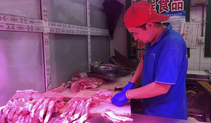 In this Wednesday, Sept. 11, 2019, photo, a butcher slices cuts of pork at a meat market in Beijing. China's government said Wednesday, Sept. 18, 2019, that is releasing pork from official stockpiles to ease a shortage and cool surging prices ahead of Oct. 1 celebrations of the Communist Party's 70th anniversary in power. (AP Photo/Fu Ting)