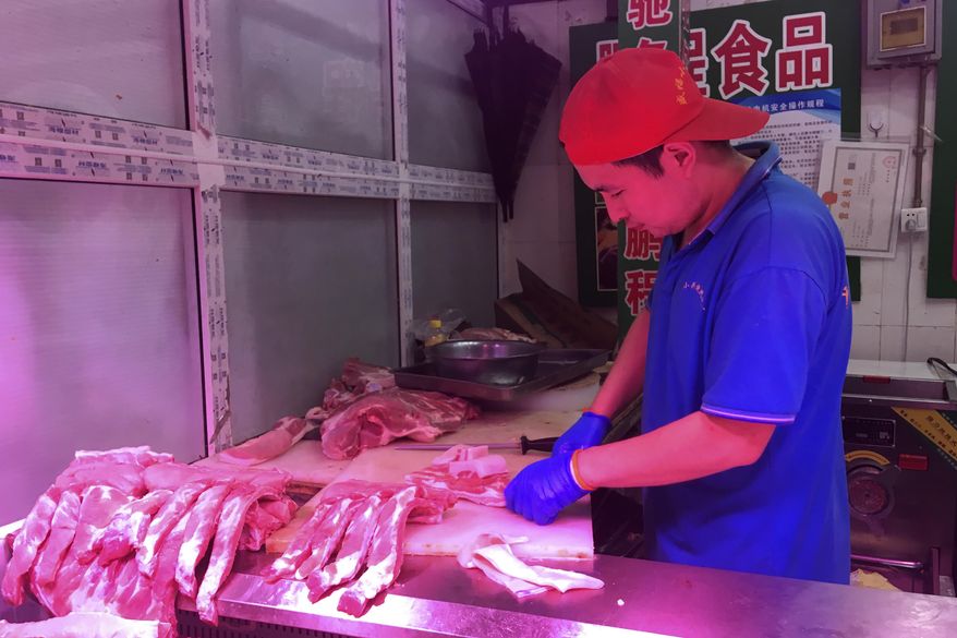 In this Wednesday, Sept. 11, 2019, photo, a butcher slices cuts of pork at a meat market in Beijing. China's government said Wednesday, Sept. 18, 2019, that is releasing pork from official stockpiles to ease a shortage and cool surging prices ahead of Oct. 1 celebrations of the Communist Party's 70th anniversary in power. (AP Photo/Fu Ting)