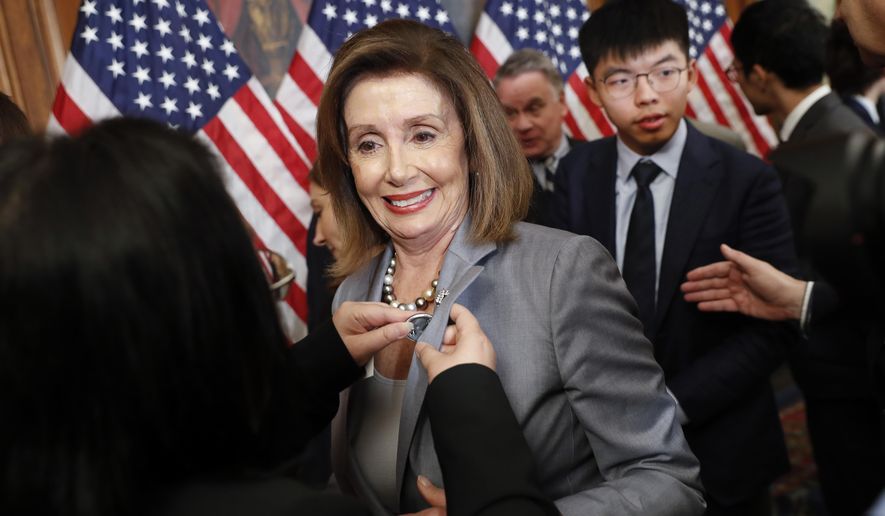 House Speaker Nancy Pelosi is given a lapel pin by a Hong Kong activist following a news conference on human rights in Hong Kong on Capitol Hill in Washington, Wednesday, Sept. 18, 2019. Behind Pelosi is Hong Kong activist Joshua Wong. (AP Photo/Pablo Martinez Monsivais)