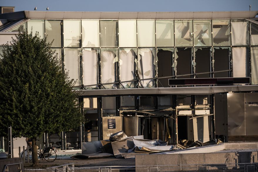 FILE - This Wednesday, Aug. 7, 2019 file photo, shows a view of the damage caused by an explosion to the entrance of the Danish Tax Authority in Copenhagen, Denmark. Police in Denmark say they have arrested a 23-year-old man late Tuesday Sept. 17, 2019, as a suspect in the explosion that damaged the headquarters of the Danish Tax Agency and slightly injured a bystander last month. (Olafur Steinar Rye Gestsson/Ritzau Scanpix via AP, File)