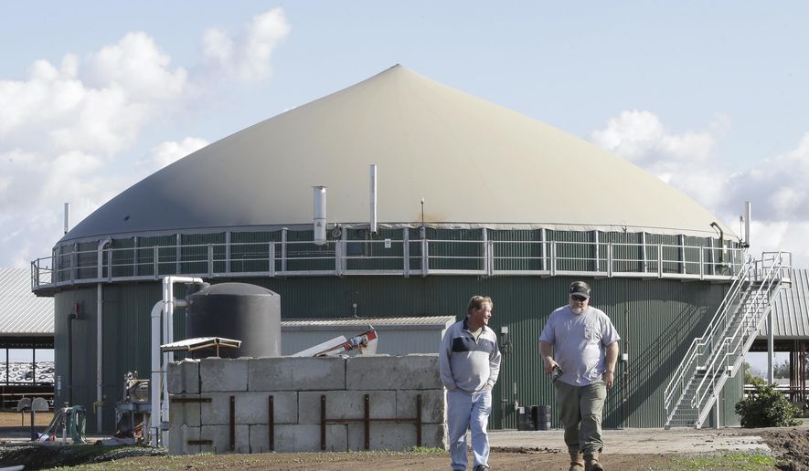 FILE - In thi, Nov. 23, 2016, photo, Arlan Van Leeuwen, left, and Arlin Van Groningen, co-owners of the new New Hope Dairy, converse as they walk near 1 million gallon storage tank used to hold raw cow manure, at the dairy in Galt, Calif. Sen. Steve Nass, a key Republican lawmaker vowed Wednesday, Sept. 18, 2019, to block new restrictions on manure storage after farmers complained state agriculture officials never consulted them and the rules are so tough they could end farm expansions in Wisconsin. (AP Photo/Rich Pedroncelli)