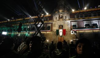 Police provide a security cordon as President Andres Manuel Lopez Obrador and first lady Beatriz Gutierrez Muller look out toward the crowd from the balcony of the National Palace, after Lopez Obrador gave the annual independence shout to kick of Independence Day celebrations at the Zocalo in Mexico City, Sunday, Sept. 15, 2019. Every year the Mexican president marks the &amp;quot;Grito de Dolores,&amp;quot; commemorating the 1810 call to arms by priest Miguel Hidalgo that began the struggle for independence from Spain, achieved in 1821.(AP Photo/Rebecca Blackwell)