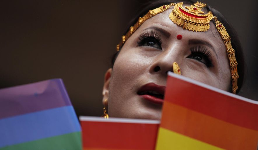 In this Aug. 16, 2019, photo, a participant holds a rainbow flag before marching in a gay pride parade in Kathmandu, Nepal. Nepal seized the lead in equal rights for sexual minorities in South Asia four years ago with a new constitution that forbids all discrimination based on sexual orientation. But activists say progress in equal rights has stalled since the constitution was adopted. (AP Photo/Niranjan Shrestha)