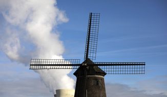 Steam rises from a nuclear power station behind an old windmill on the River Scheldt in Doel, Belgium, Thursday, Sept. 19, 2019. Political leaders meet Sept. 23, 2019, for a climate summit in New York to ramp up global efforts to tackle the climate crisis. (AP Photo/Virginia Mayo)