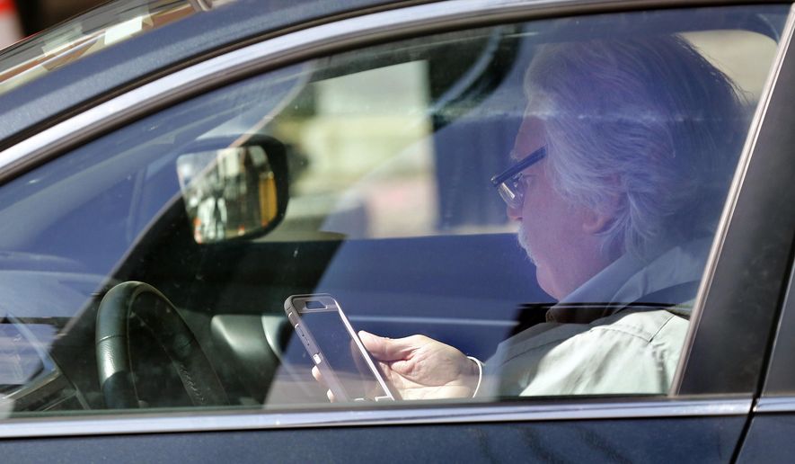 In this Thursday, May 16, 2019 photo, a driver uses his cell phone while driving in Portland, Maine. A bill to ban the use of handheld cellular devices while driving in the state goes into effect on Thursday, Sept. 19. (AP Photo/Robert F. Bukaty)