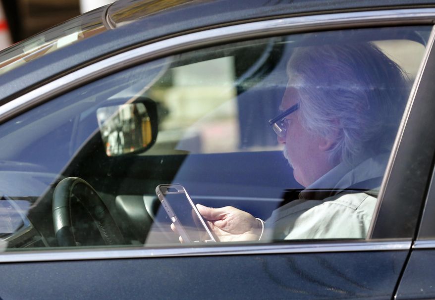 In this Thursday, May 16, 2019 photo, a driver uses his cell phone while driving in Portland, Maine. A bill to ban the use of handheld cellular devices while driving in the state goes into effect on Thursday, Sept. 19. (AP Photo/Robert F. Bukaty)