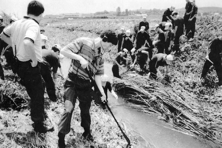 CORRECTS TO KILLING INSTEAD OF MURDER - In this July, 1993, photo, South Korean investigators examine the scene following a killing in Hwaseong, South Korea. South Korean police have found a man who could be an infamous serial killer wanted for the slaying of nine women some 30 years ago, officials said Thursday, Sept. 19, 2019, 13 years after the statute of limitations expired over the unresolved criminal cases. (Yonhap via AP)