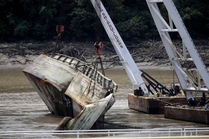 In this Tuesday, Aug. 27, 2019 photo, one of two sunken barges is removed from the Webbers Falls Lock and Dam 16. The barges broke loose up river and sunk during May's historic flooding. U.S. Sen. Jim Inhofe says an Arkansas River system that runs from Tulsa to the Mississippi River is facing a $225 million backlog of maintenance projects after being hindered for months this summer by historic flooding in Oklahoma. (Mike Simons/Tulsa World via AP)