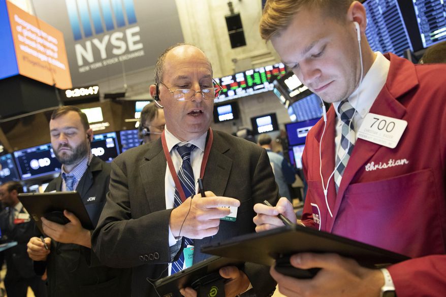 FILE - In this Sept. 16, 2019, file photo Gordon Charlop, center, and Christian Bader work at the New York Stock Exchange. The U.S. stock market opens at 9:30 a.m. EDT on Friday, Sept. 20. (AP Photo/Mark Lennihan, File)