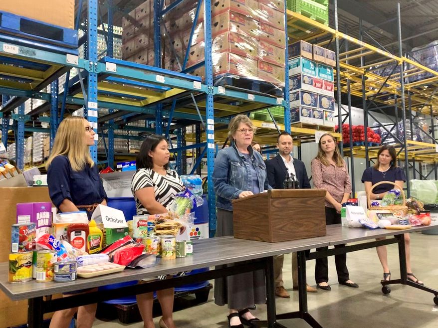 Colleen Moriarty, executive director of Hunger Solutions Minnesota, center, stands alongside other nonprofit leaders in opposition to the federal government's proposed changes to the Supplemental Nutrition Assistance Program, SNAP, which would cut 35,500 Minnesotans off food assistance in St Paul, Minn. The stacks of food illustrate how much food one family would lose a month. (Kelly Smith/Star Tribune via AP)