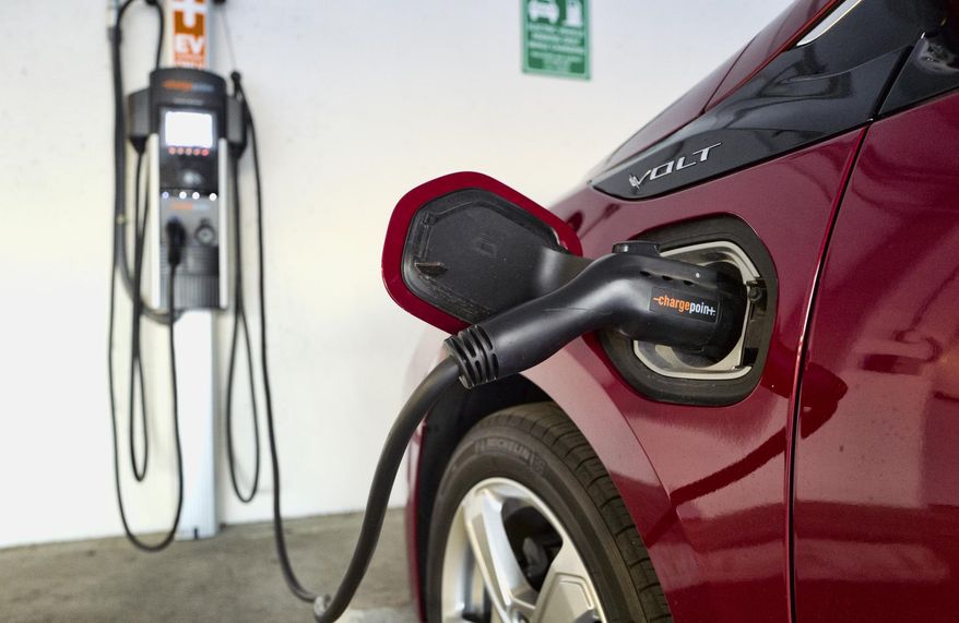 FILE - This Wednesday, Oct. 17, 2018 file photo shows a Chevrolet Volt hybrid car charging at a ChargePoint charging station at a parking garage in Los Angeles. If U.S. consumers ever ditch fuel burners for electric vehicles, then the United Auto Workers union is in trouble. Gone would be thousands of jobs at engine and transmission plants across the industrial Midwest, replaced by smaller workforces at squeaky-clean mostly automated factories that mix up chemicals to make batteries. (AP Photo/Richard Vogel, File)
