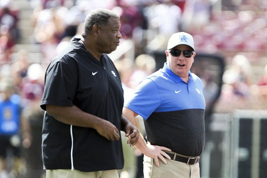 Kentucky head coach Mark Stoops talks with Kentucky associate head coach Vince Marrow during warmups prior to an NCAA college football game against Mississippi State, Saturday, Sept. 21, 2019, in Starkville, Miss. (AP Photo/Kelly Donoho)