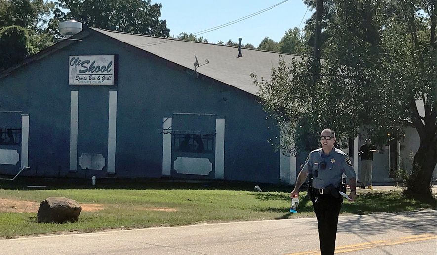 A Lancaster County Sheriff's deputy walks around the Old Skool Sports Bar and Grill, the scene of a shooting early in the morning, north of Lancaster, S.C. on Saturday, Sept. 21, 2019. Lancaster County Sherriff's Office said in a statement that the agency was investigating a fatal shooting that also injured several people. (Jessica Holdman/The Post And Courier via AP)