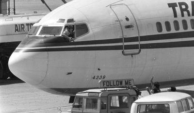 A Shiite Muslim hijacker points his pistol toward an ABC news media crew from the window of the cockpit of the Trans World Airlines jet as the American television crew approaches the jet for an interview at Beirut International Airport, Lebanon, Wednesday, June 19, 1985. (Associated Press)