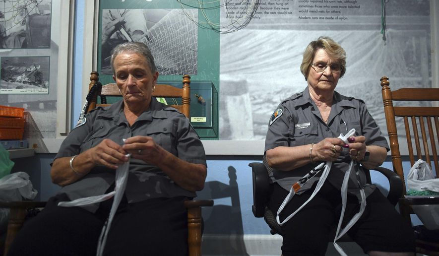 In this Aug. 20, 2019 photo, Nannette Wall, left, 67, and Ethel Ford, 70, sit in rocking chairs in Sebastian, Fla., weaving strands of plastic bags, known as "plarn", to be used as material for handbags, coasters and sleeping mats. Known as the "Recycling Grannies", Wall and Ford are volunteers at the Sebastian Inlet State Park and both agree the plastic they use will not negatively impact the park that they love. (Patrick Dove/TCPalm.com via AP)