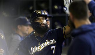 Milwaukee Brewers&#39; Eric Thames is congratulated in the dugout after hitting a solo home run during the fourth inning of a baseball game against the Pittsburgh Pirates, Sunday, Sept. 22, 2019, in Milwaukee. (AP Photo/Aaron Gash)