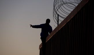 A Mexican citizen gestures after climbing the border fence to take pictures of himself, in Tijuana, Mexico, Sunday, Nov. 18, 2018. (AP Photo/Ramon Espinosa) **FILE**