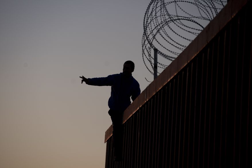 A Mexican citizen gestures after climbing the border fence to take pictures of himself, in Tijuana, Mexico, Sunday, Nov. 18, 2018. (AP Photo/Ramon Espinosa)