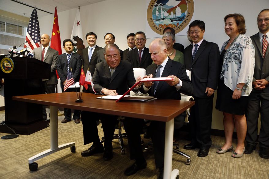 FILE - In this Sept. 13, 2014, file photo, California Gov. Jerry Brown, front right, and China&#39;s National Development and Reform Commission Vice Chairman Xie Zhenhua, front left, sign an agreement to boost bilateral cooperation on climate change during a news conference at the Bay Area Council, in San Francisco. As tensions between China and the United States ratchet up, former California Gov. Jerry Brown sees a way to bring together the world&#39;s largest carbon emitter and a U.S. state that&#39;s leading the way in energy standards: climate change. (AP Photo/Beck Diefenbach,file)