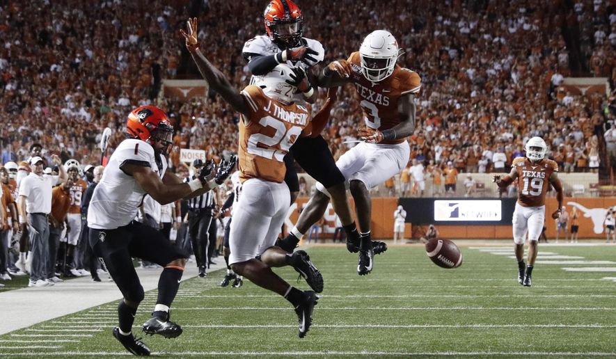 Texas defensive back Josh Thompson (29) and defensive back Jalen Green (3) break up a pass intended for Oklahoma State wide receiver Tylan Wallace (2) during the first half of an NCAA college football game Saturday, Sept. 21, 2019, in Austin, Texas. (AP Photo/Eric Gay)