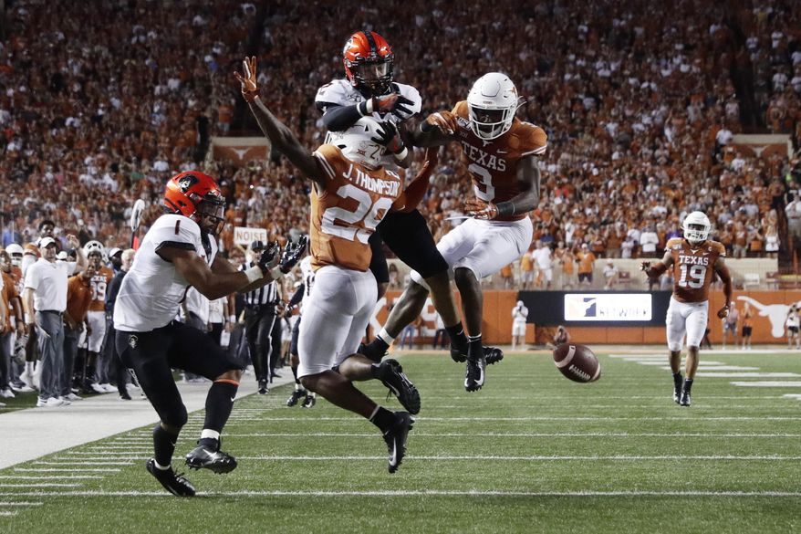 Texas defensive back Josh Thompson (29) and defensive back Jalen Green (3) break up a pass intended for Oklahoma State wide receiver Tylan Wallace (2) during the first half of an NCAA college football game Saturday, Sept. 21, 2019, in Austin, Texas. (AP Photo/Eric Gay)