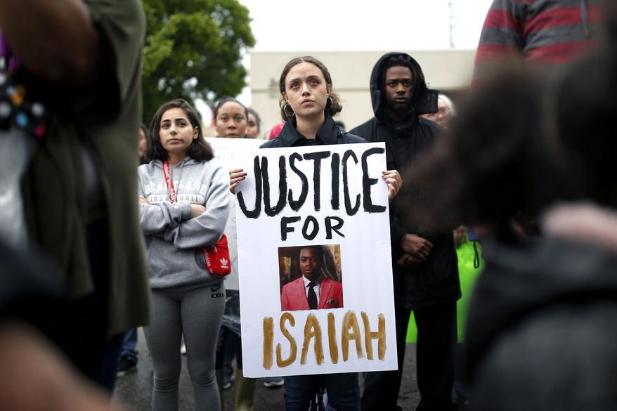 FILE - In this May 3, 2019, file photo, a protester holds a sign at the Edmond Police Department during a Black Lives Matter protest rally honoring the life of Isaiah Lewis, in Edmond, Okla. A prosecutor says police in Edmond were justified when they fatally shot Lewis, who was naked and unarmed. Oklahoma County District Attorney David Prater said Monday, Sept. 23, 2019, he could not find probable cause to file criminal charges against Edmond Police Department Sgt. Milo Box and Officer Denton Scherman for the April 29 shooting death of 17-year-old Lewis. (Sarah Phipps/The Oklahoman via AP, File)