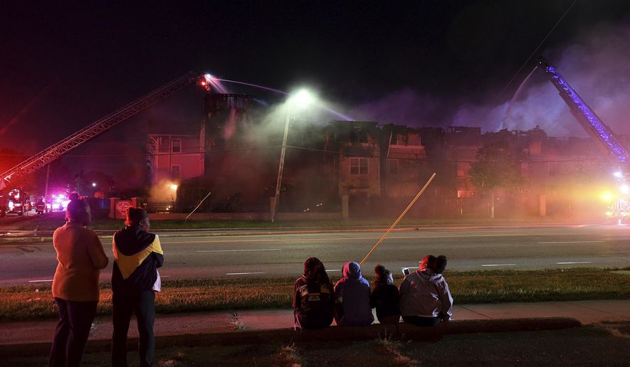 In this Monday, Sept. 23, 2019 photo, people watch as members of multiple Detroit fire engine and ladder units battle a fire at the Reverend Ann Johnson Elderly Apartments in Detroit. Dozens of seniors were displaced by the fire in the 54 unit building. (Robin Buckson/Detroit News via AP)