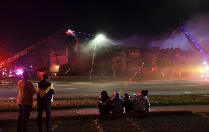 In this Monday, Sept. 23, 2019 photo, people watch as members of multiple Detroit fire engine and ladder units battle a fire at the Reverend Ann Johnson Elderly Apartments in Detroit. Dozens of seniors were displaced by the fire in the 54 unit building. (Robin Buckson/Detroit News via AP)
