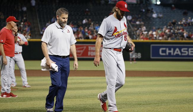 Injured St. Louis Cardinals starting pitcher Michael Wacha, right, walks off the field with head athletic trainer Adam Olsen, middle, as Cardinals pitching coach Mike Maddux, left, looks to the bullpen during the second inning of a baseball game against the Arizona Diamondbacks Wednesday, Sept. 25, 2019, in Phoenix. (AP Photo/Ross D. Franklin)