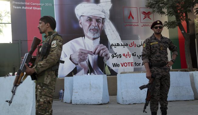 In this Monday, Sept. 23, 2019, photo, Afghan security forces stand guard in front of an election poster for presidential candidate Ashraf Ghani in Kabul, Afghanistan. Millions of Afghans are expected to go to the polls on Saturday to elect a new president, despite an upsurge of violence in the weeks since the collapse of a U.S.-Taliban deal to end Americas longest war, and the Taliban warning voters to say away from the polls. (AP Photo/Rahmat Gul)