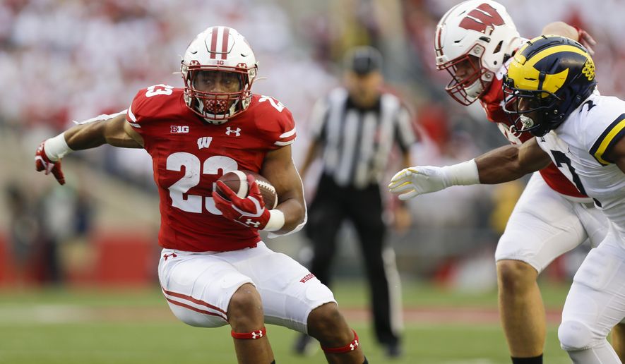 Wisconsin running back Jonathan Taylor runs against Michigan linebacker Khaleke Hudson during the first half of an NCAA college football game Saturday, Sept. 21, 2019, in Madison, Wis. (AP Photo/Andy Manis)