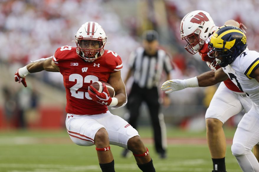 Wisconsin running back Jonathan Taylor runs against Michigan linebacker Khaleke Hudson during the first half of an NCAA college football game Saturday, Sept. 21, 2019, in Madison, Wis. (AP Photo/Andy Manis)