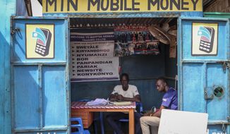 In this photo taken Tuesday, Sept. 10, 2019, a man sits in his mobile money kiosk which specializes in sending money from South Sudan to Uganda, in the capital Juba, South Sudan. South Sudan has launched mobile money, the ability to send and receive funds by phone, in an attempt to boost the economy after a five-year civil war killed almost 400,000 people. (AP Photo/Sam Mednick)