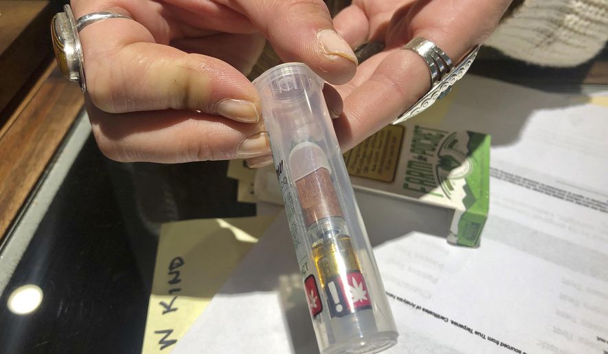In this photo taken Sept. 20, 2019, Cameron Moore, general manager of Bridge City Collective in Portland, Ore., holds a vape cartridge that&#39;s on sale at the dispensary. (AP Photo/Gillian Flaccus)