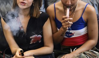 In this Saturday, June 8, 2019, file photo, two women smoke cannabis vape pens at a party in Los Angeles. (AP Photo/Richard Vogel) ** FILE **