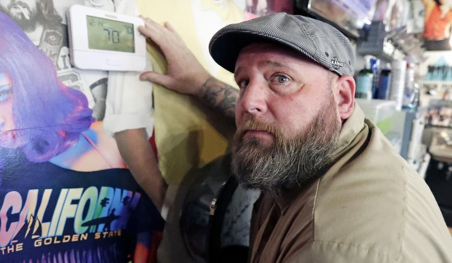 In this Wednesday, Sept. 25, 2019 photo, George Johnson points to a thermostat at the barber shop where he works in Longwood, Fla. Johnson says he rarely uses public transportation but is worried about climate change and keeps his driving to a minimum. He sometimes takes other conservation steps such as eating vegetarian meals and planting trees while always turning off unnecessary lights. “You’ve got to start somewhere,” he said. “If everybody just turned off their lights one hour or anything, it can help.” (AP Photo/John Raoux)