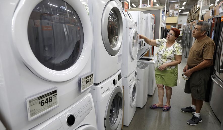 In this Monday, Sept. 23, 2019 photo Maria Alvarez, left, and her husband Guillermo Alvarez, right, both of Boston, examine clothes washers and dryers at a Home Depot store location, in Boston. On Friday, Sept. 27, the Commerce Department releases its August report on durable goods. (AP Photo/Steven Senne)