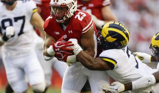 Wisconsin running back Jonathan Taylor, left, runs against Michigan&#39;s Khaleke Hudson, right, during the first half of an NCAA college football game Saturday, Sept. 21, 2019, in Madison, Wis. (AP Photo/Andy Manis)