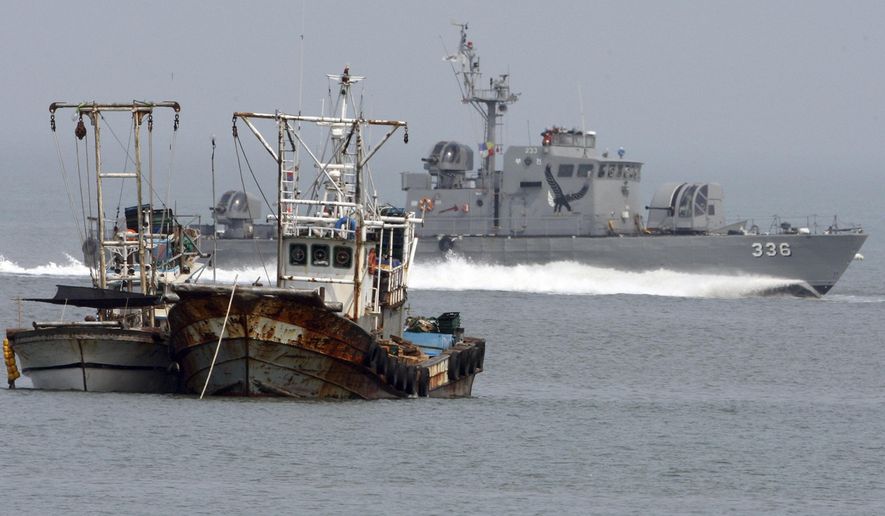 FILE- In this May 29, 2009, file photo, a South Korean navy vessel passes by fishing boats near Yeonpyong Island, off the northwest coast of South Korea, May 29, 2009. South Korea's military on Friday, Sept. 27, 2019, says it fired warning shots toward a North Korean boat crossing their sea border, then it sent a navy mechanic to repair the drifting boat's engine so it could return to the North. (Ahn Jong-won/Yonhap via AP)