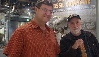 This Tuesday, Sept. 24, 2019, photo shows Smithsonian National Museum of Natural History Director Kirk Johnson, left, and Ketchikan artist Ray Troll posing for photos at a traveling exhibition inspired by their collaborative book at the Alaska State Museum in Juneau, Alaska. Johnson gave a speech at the museum since it is the current site of a traveling exhibit inspired by he and Troll&#39;s collaborative efforts and a trip along most of North America&#39;s western coast. (Ben Hohenstatt/Capital City Weekly via AP)